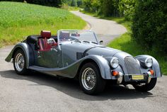 an old fashioned sports car is parked on the road