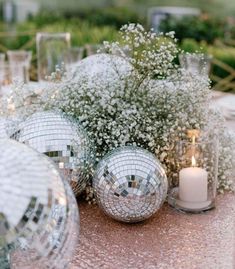 silver disco ball centerpieces with baby's breath flowers and candles on a table