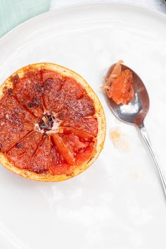 a grapefruit on a white plate with a spoon