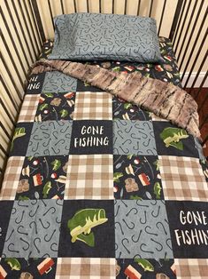 a baby crib bed with a gone fishing quilt on it's coverlet