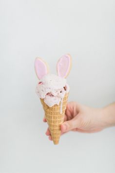 someone holding an ice cream cone with bunny ears on it