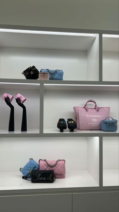 several purses and handbags are on display in a white shelving with grey shelves