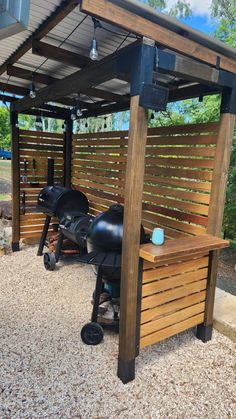 an outdoor bbq with grills and chairs under the pergolated roof area