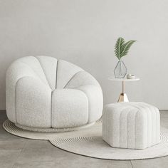 a white chair and ottoman with a plant in the corner next to it on a rug