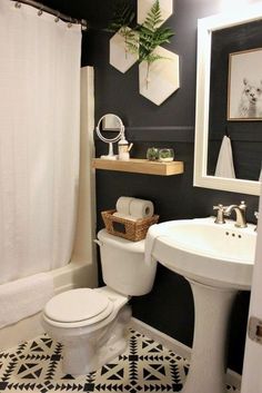 a white toilet sitting next to a sink in a bathroom under a mirror and shower curtain