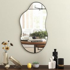 a mirror sitting on top of a wooden table next to vases and other items