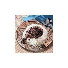 a plate topped with rice and black beans next to a fork on top of a table