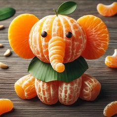 an elephant made out of oranges sitting on top of a wooden table with leaves