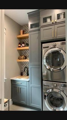 a washer and dryer are in the corner of this laundry room with built - in shelving