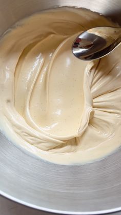 a metal bowl filled with cream and a spoon