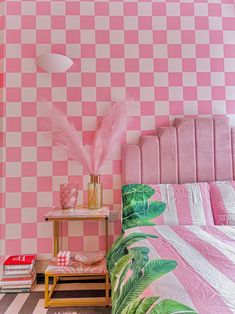 a bedroom with pink and white checkered wallpaper, palm leaves on the bed