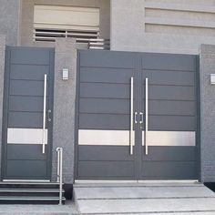 two large gray doors on the side of a building with stairs leading up to them