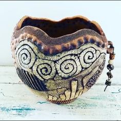 a ceramic bowl sitting on top of a white wooden table next to a beaded necklace