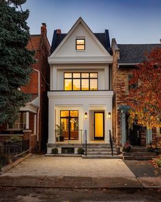 a white two story house with lots of windows and steps leading up to the front door