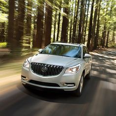 a silver car driving down a forest road