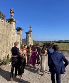 a group of people standing around each other in front of a stone wall and gate