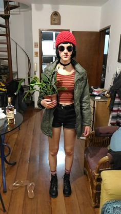 a woman standing in a living room holding a potted plant