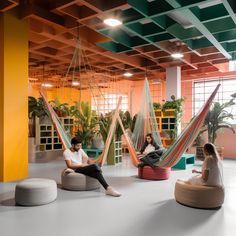 two people sitting in hammocks inside an office