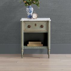 a small table with a clock and flowers on it