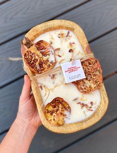 a hand holding a tray with some food in it and a tag on the top