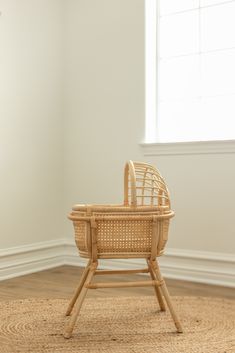 an empty wicker chair sitting on top of a rug in front of a window