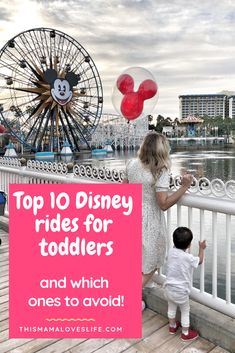 a woman and child standing on a pier with mickey mouse balloons in front of them