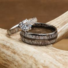 two wedding rings sitting on top of a piece of driftwood next to each other