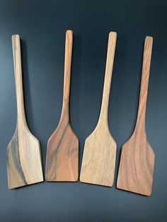 three wooden utensils are lined up against a black background and one is made from wood