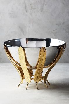 there is a silver bowl with gold feathers in it and the words stars of the holiday table