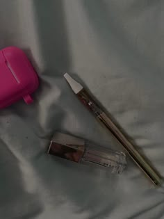 a pink container with a toothbrush next to it on a white sheeted surface