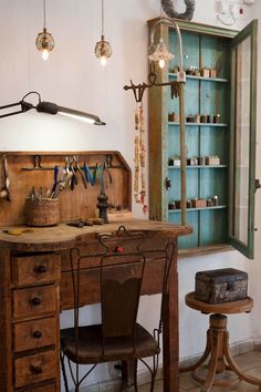 an old wooden desk with lots of tools hanging from the wall and on top of it