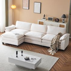 a living room with a white sectional couch and coffee table on the floor in front of it