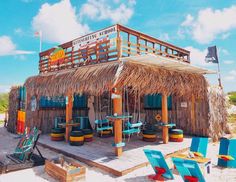 a tiki bar on the beach with lounge chairs