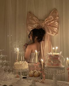 a woman standing in front of a table filled with cakes and cupcakes