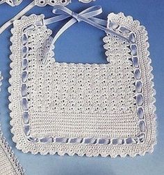 a white crocheted bib hanging from a hook on a blue wall with a ribbon