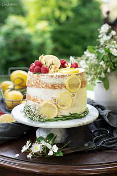 a cake with lemons, raspberries and other fruits on it sitting on a table