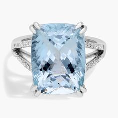 an aqua blue topazte ring with diamonds on the sides and side stones around it