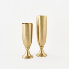 two gold colored vases sitting side by side on a white surface, one is empty