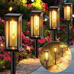 four lights that are on the side of a sidewalk in front of flowers and bushes