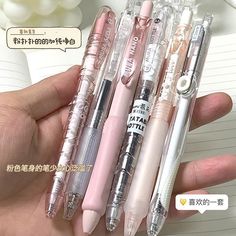 three pens are in the palm of someone's hand, one is pink and one is white