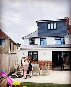 two women standing in front of a house