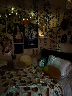 an unmade bed with lots of pictures on the wall and lights hanging above it