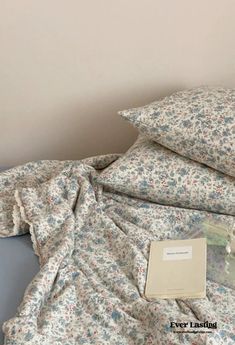 an unmade bed with two pillows and a book on the pillowcase next to it