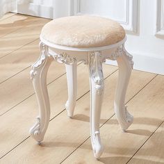 a white stool with a beige cushion on top of wooden flooring next to a door