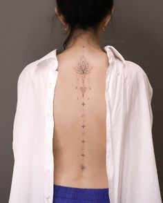 the back of a woman's neck with a flower tattoo on her left side