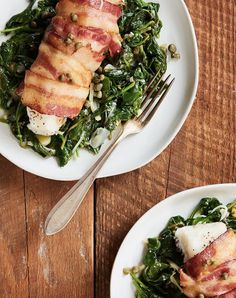 two white plates topped with bacon and greens