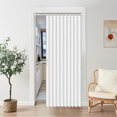 a living room with white curtains and a chair in front of the door that is open