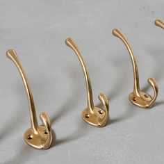 four brass handles are shown on a gray surface, one has a hook and the other has a loop