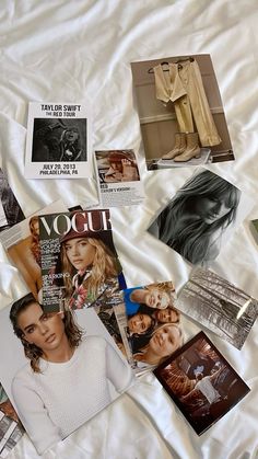 many magazines and photos are spread out on a bed sheet with white sheets in the background