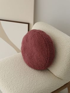 a round pillow sitting on top of a white chair